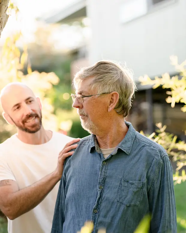 An experienced person resting a reassuring hand on someone's shoulder outdoors