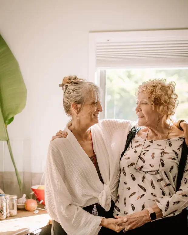 Two people smiling warmly together in a sunlit kitchen